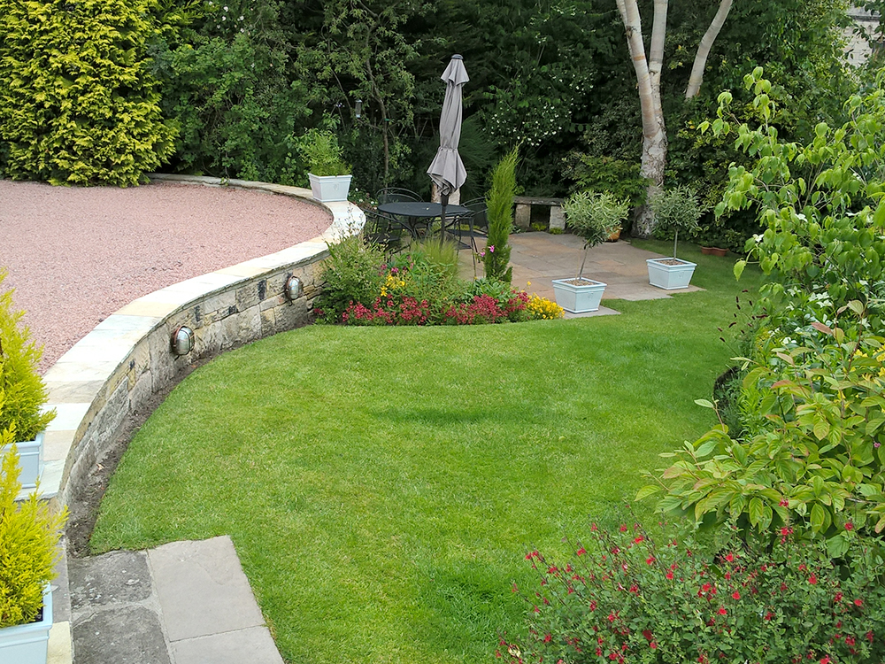 Stone driveway with step down to garden with patio area