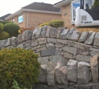 Large stone natural walling with bobcat digger